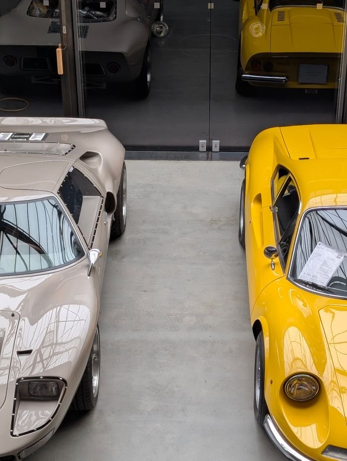 A vintage car and a yellow sports car photographed indoors at a classic car showroom in Berlin.